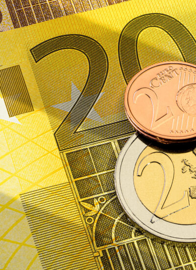 Différentes pièces en euros, une pièce d'un euro et une pièce d'un cent, posées sur un billet de 200 euros jaune.